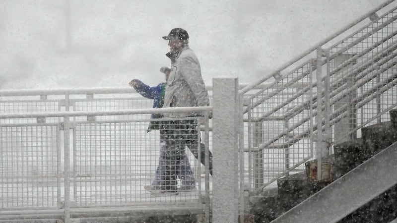 Aficionados al hockey se dirigen al Ball Arena mientras una nevada de primavera pasa por la...