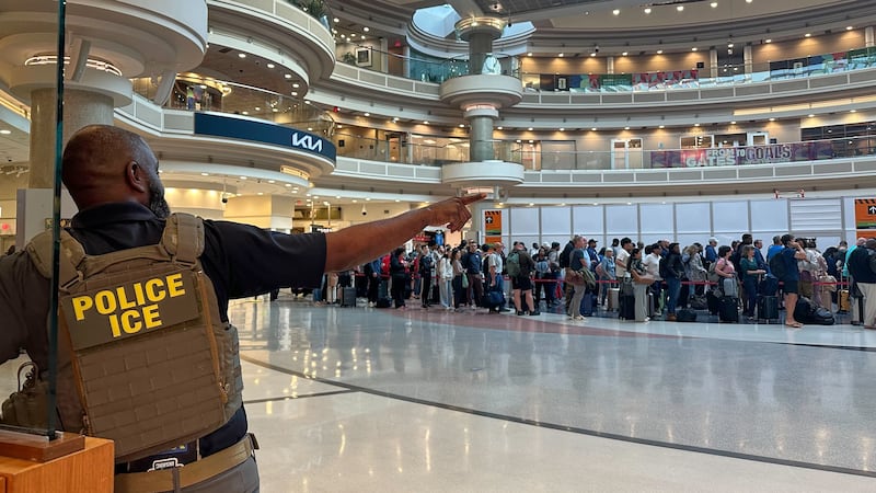 A federal immigration agent is seen as people wait in a TSA line at the Hartsfield-Jackson...