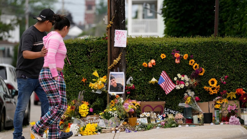 Unas personas pasan junto a un memorial improvisado para un hombre muerto a tiros por agentes...