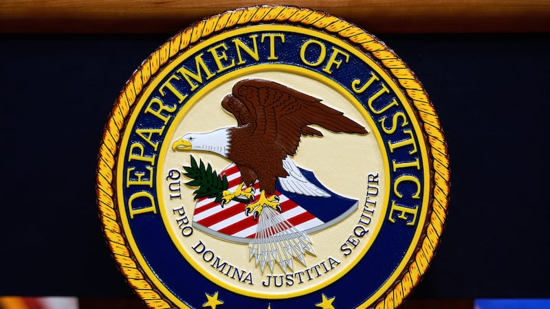 FILE - The U.S. Department of Justice logo is seen on a podium before a press conference, May...