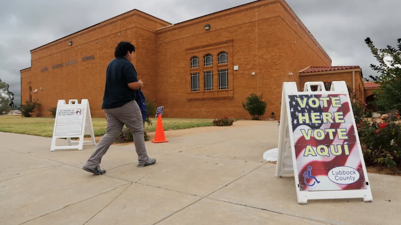 A voter walks past an election sign on his way to vote outside of the Lauro Cavazos Middle...